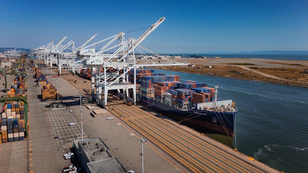 Aerial view of cargo ship and containers at Port of Oakland under clear skies.