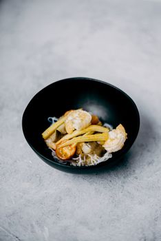 深色碗中优雅地盛放着虾和玉米，这是一道美味的亚洲风味菜肴