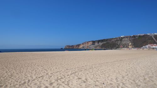 Free A picturesque beach with clear skies and cliffs in Portugal, perfect for travel and nature enthusiasts. Stock Photo