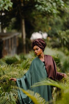 A woman in a green gown amidst lush greenery, displaying elegance and serenity.