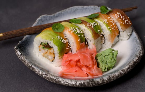 Tasty sushi roll garnished with avocado, salmon, wasabi, and pickled ginger.