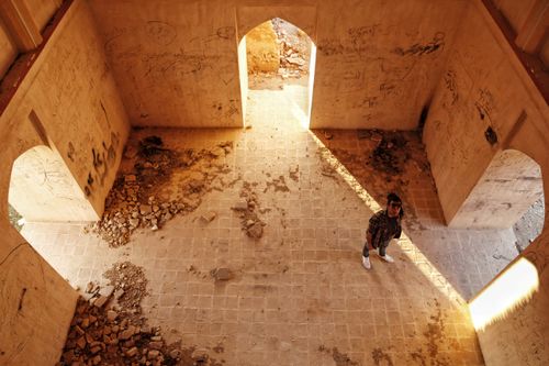 Free A person stands inside a sunlit, abandoned building with graffiti-covered walls. Stock Photo