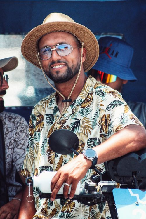 Free Man wearing a straw hat and tropical shirt, smiling joyfully outdoors. Stock Photo