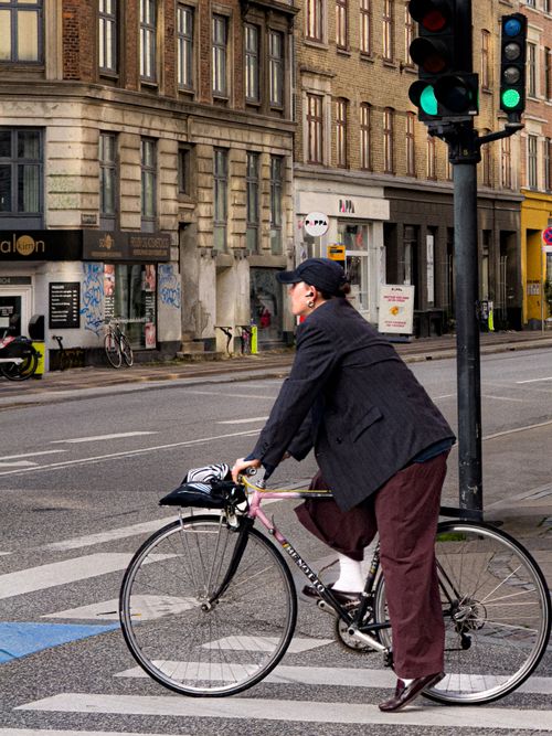 Free Man on a bike at a city intersection under green traffic lights. Stock Photo