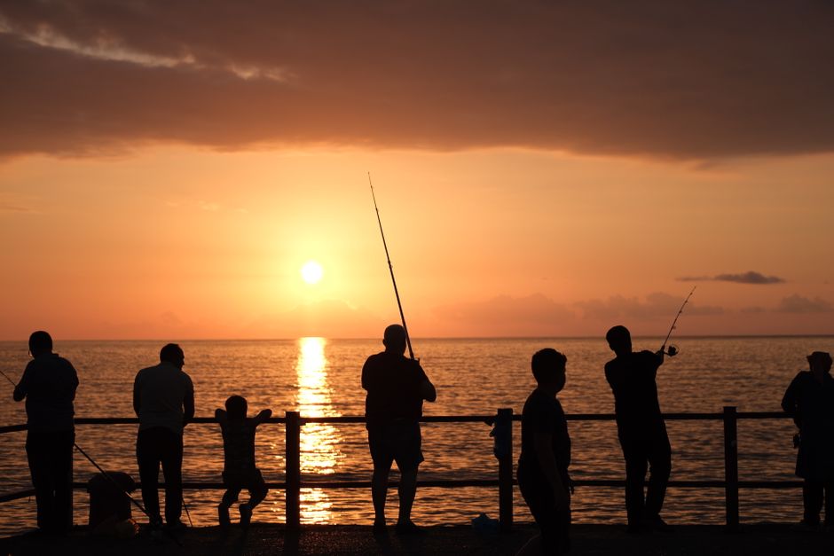 朝マズメの釣りで竿を持つ早朝の海岸