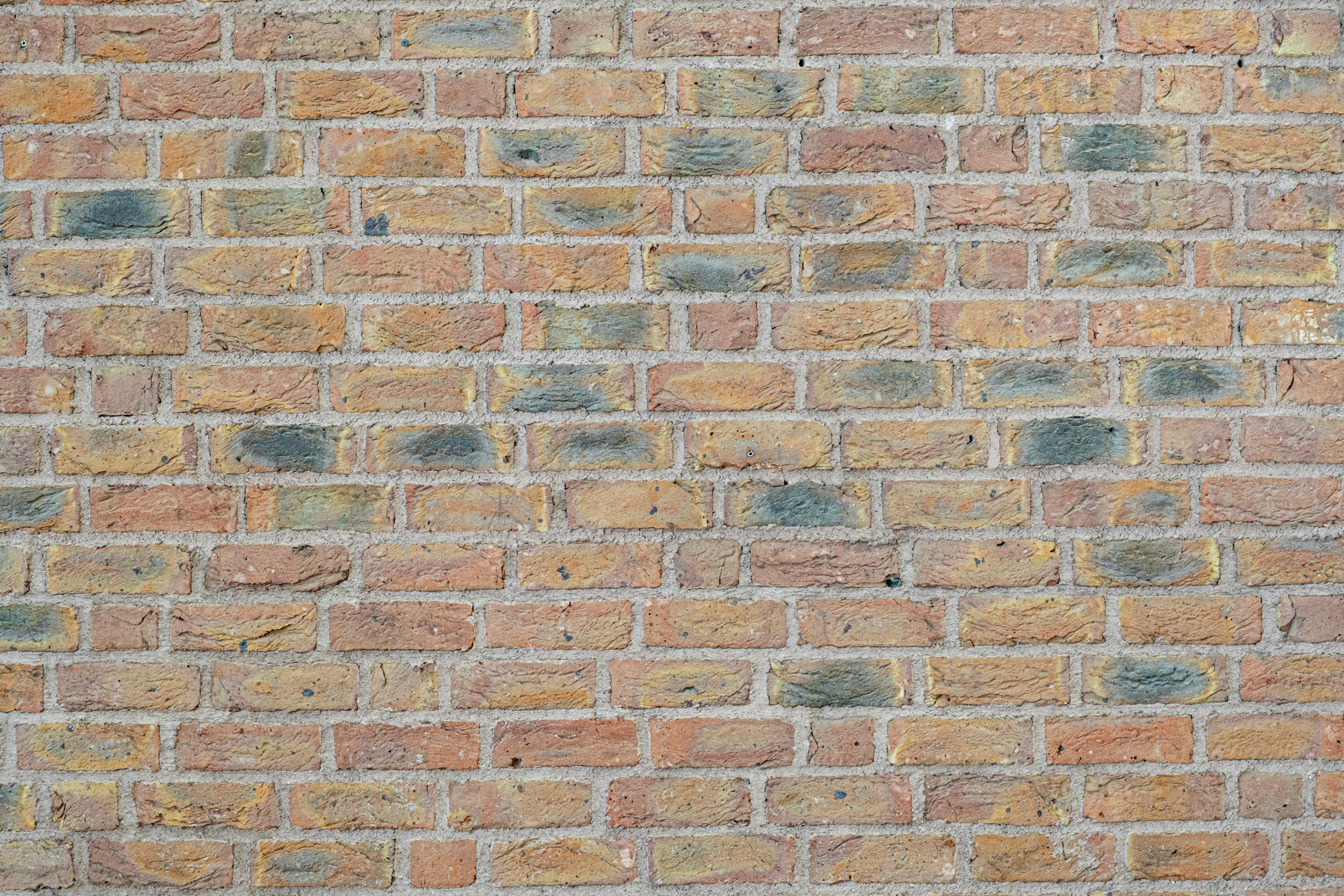 Gratis Primer plano detallado de una pared de ladrillos multicolores que ofrece un fondo texturizado. Foto de stock