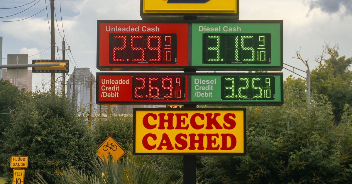 Photo by Eddie O. Gas station signboard displaying fuel prices and checks cashed in Houston, TX.