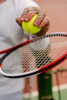 Close-up view of a person holding a tennis ball on a racket on the court.