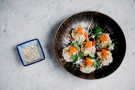 亚洲饺子的顶视图，上面装饰着鱼子和香菜，并配有芝麻