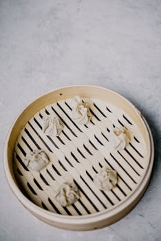 A top view of six handmade dumplings in a traditional bamboo steamer.