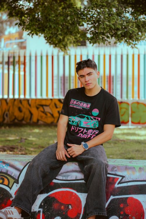Free Young man sitting on graffiti wall under tree, urban street style. Stock Photo
