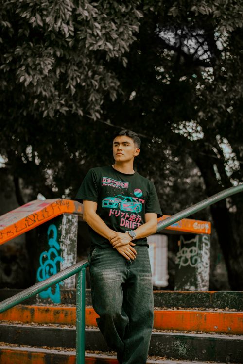 Free Casually dressed young man standing on a graffiti-covered staircase outdoors. Stock Photo