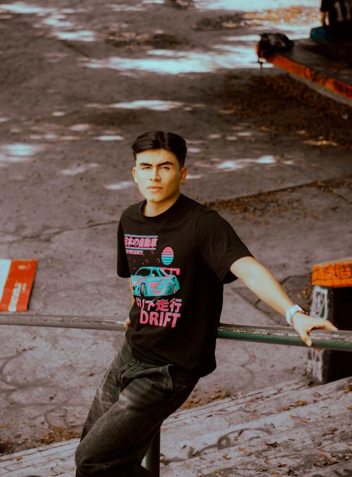 Free Casual young man leaning on rail in urban setting, stylish streetwear. Stock Photo