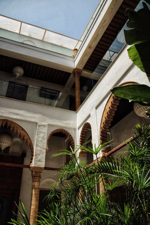 Free Beautiful Moroccan courtyard featuring traditional arches and lush greenery under a clear blue sky. Stock Photo