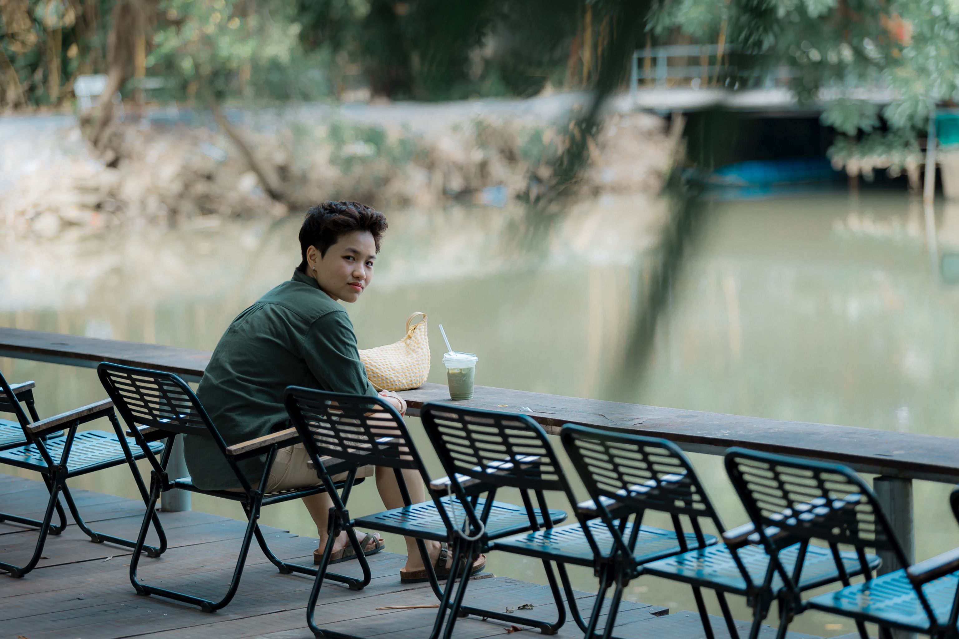 A person relaxing by the riverside, enjoying a cool beverage outdoors.