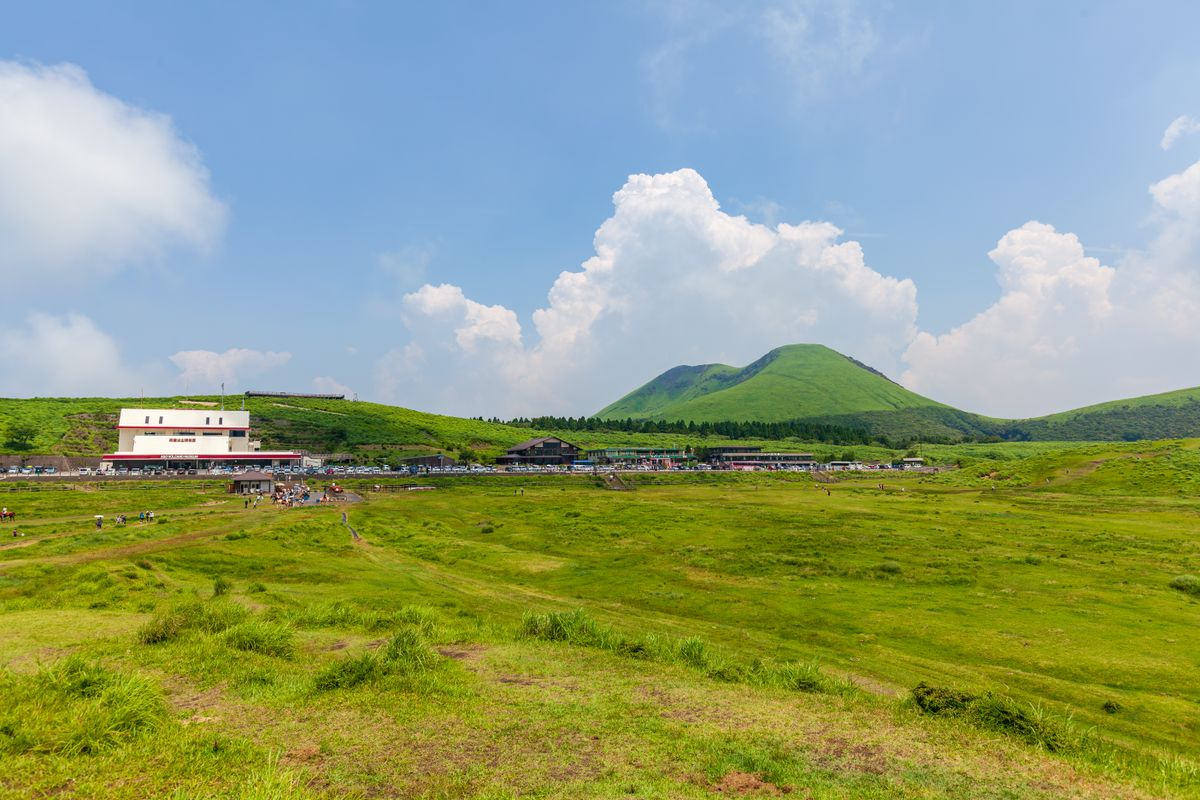 Mount Aso's vast green caldera plateau with Komezuka cone volcano in the background — the landscape that defines Kumamoto Prefecture