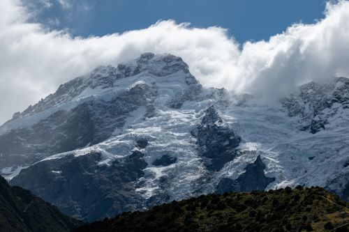 Free Breathtaking view of Aoraki / Mount Cook with its snow-covered peaks surrounded by clouds in the Canterbury Region, New Zealand. Stock Photo
