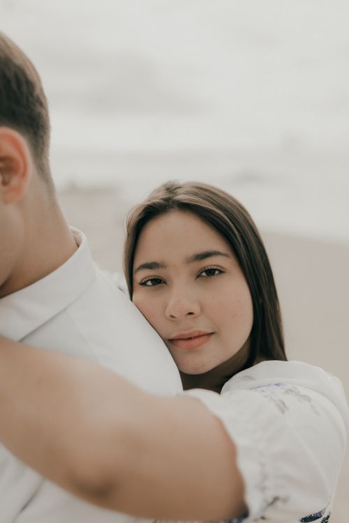 Free A young woman embraces a man gently on a serene beach, exuding warmth and connection. Stock Photo