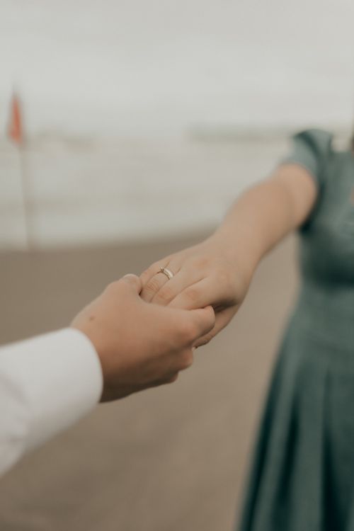 Free Close-up of a couple holding hands on a beach, symbolizing love and connection. Stock Photo