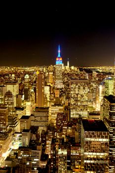 Breathtaking aerial night view of New York City skyline featuring illuminated skyscrapers and Empire State Building.