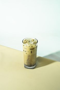 A tall glass of iced coffee with ice cubes on a soft, light background. Minimalist and refreshing.