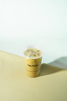 A refreshing iced coffee in a sealed plastic cup placed on a table with a soft background.