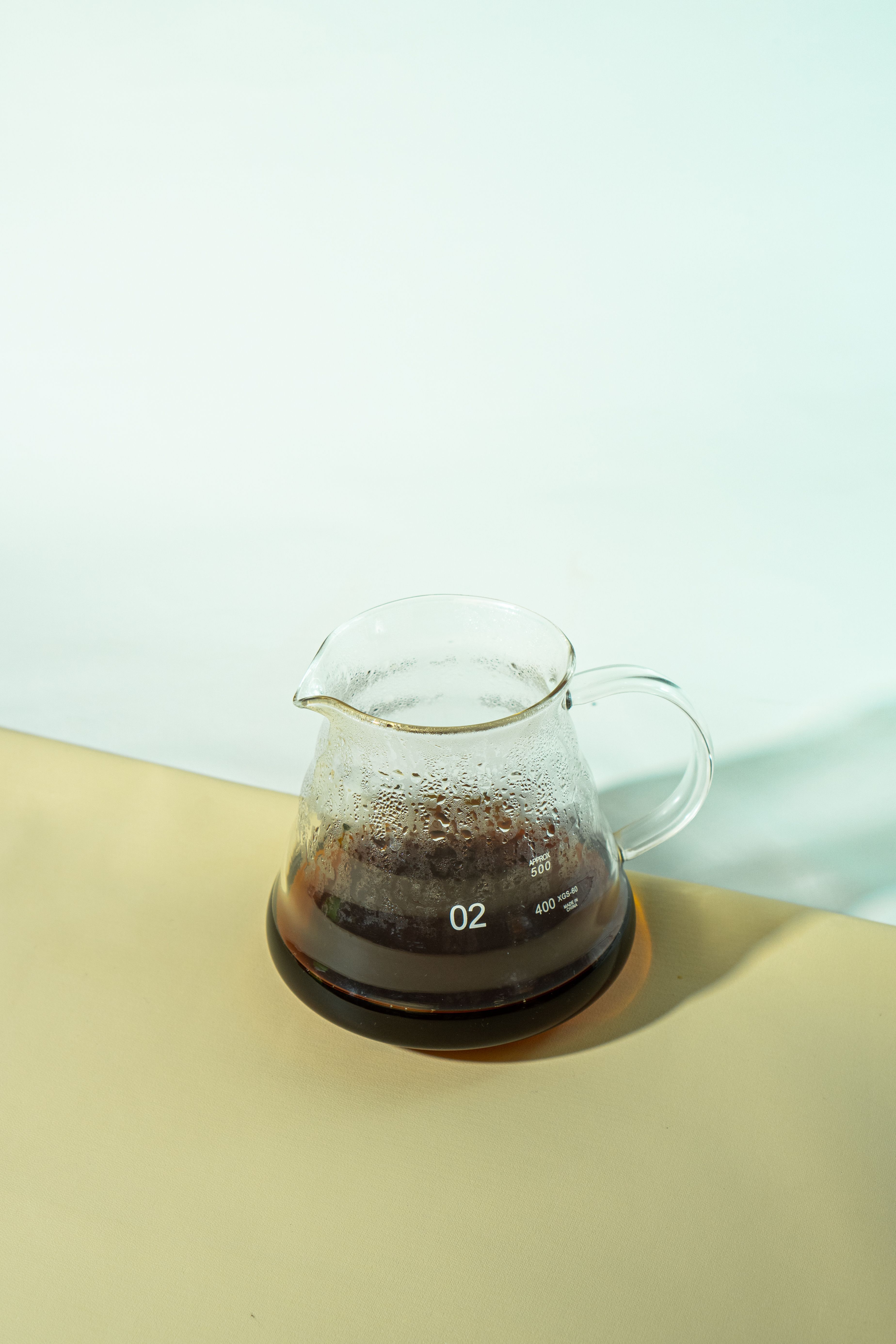 Gratis Una caraffa di vetro trasparente contenente caffè appena fatto su una superficie neutra. Foto a disposizione