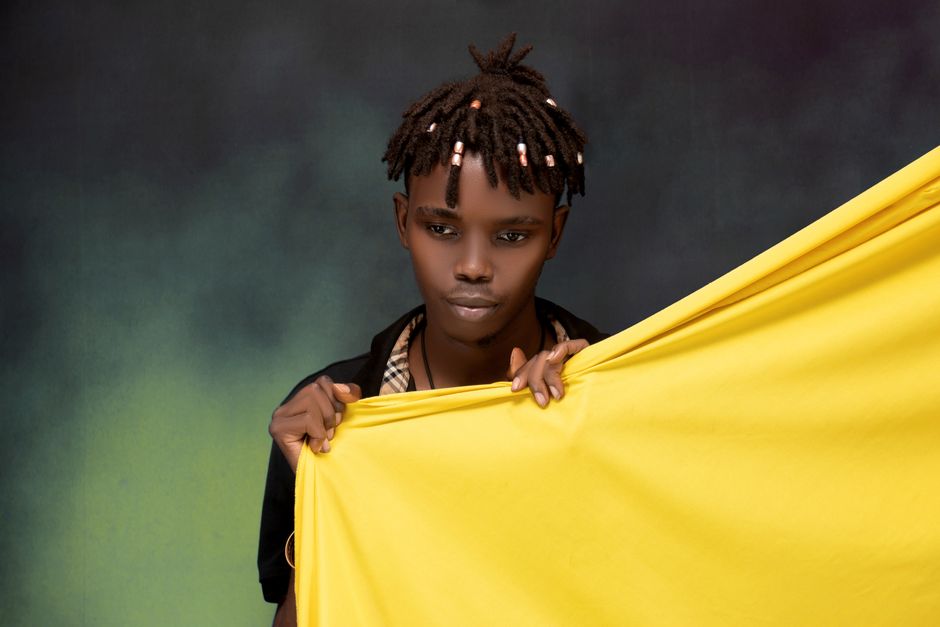 아이폰17 |모델·용량 선택 가이드 12 Portrait of a stylish young man holding yellow fabric in a studio setting, showcasing fashion and creativity.