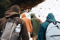 冬天，一群徒步旅行者背着背包，行走在白雪皑皑的山间小道上