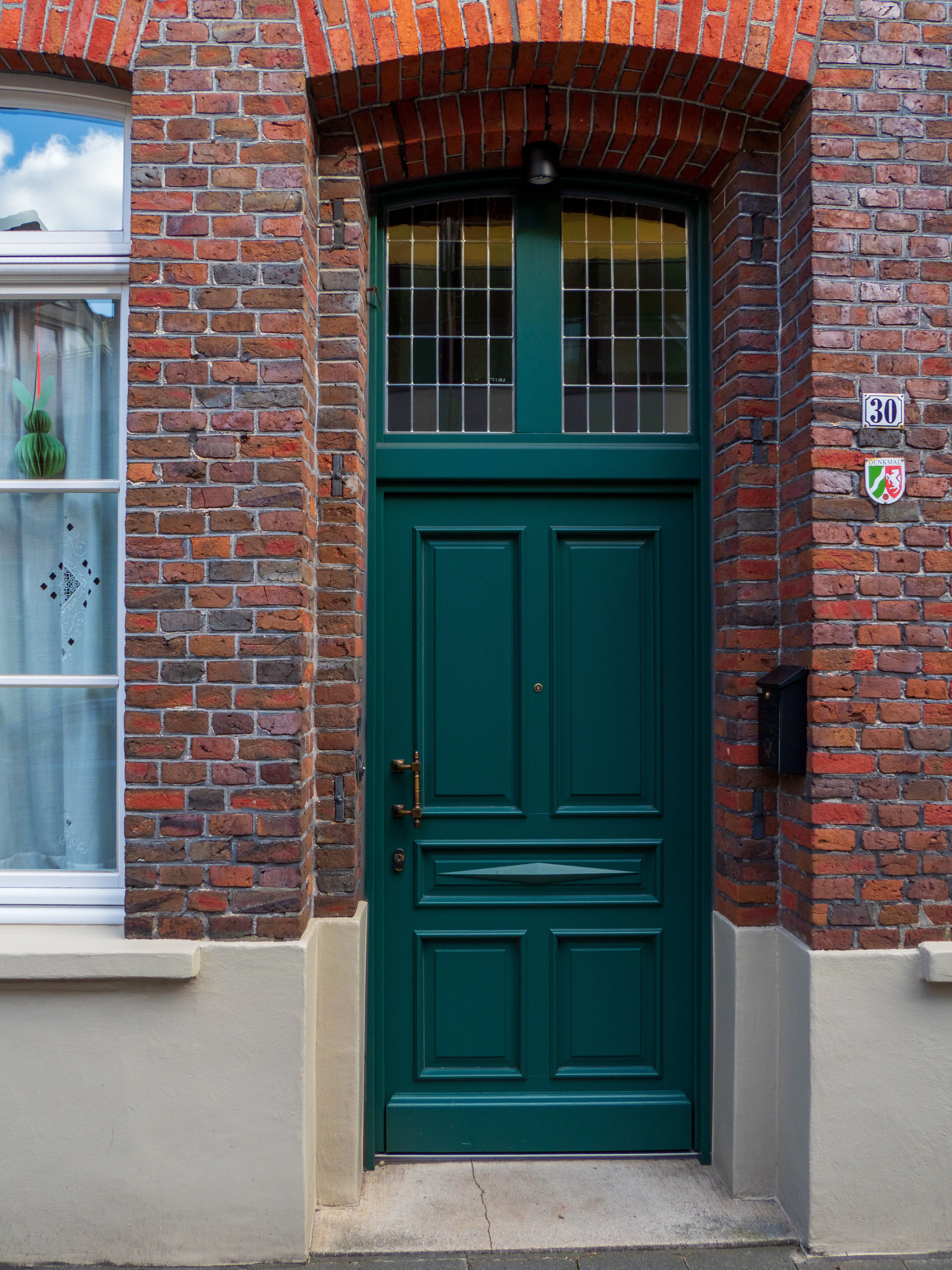 Elegant green door set in red brick building facade, number 30 displayed clearly.