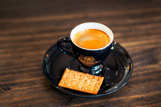 Close-up of a steaming espresso cup with biscuit on a wooden table. Ideal for coffee-themed stock photography.