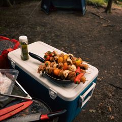 A blue cool box with a white lid used as a camp table