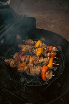 Close-up of mouthwatering chicken skewers with vibrant peppers on a grill, perfect for outdoor barbecues.