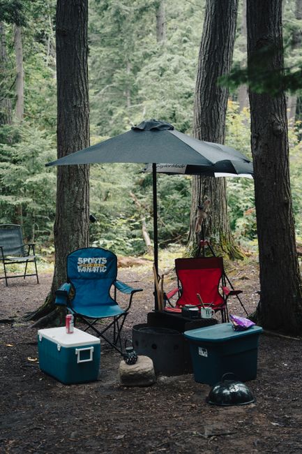 A tidy car camping campsite with a tent, camp chairs, and an organized kitchen setup at golden hour