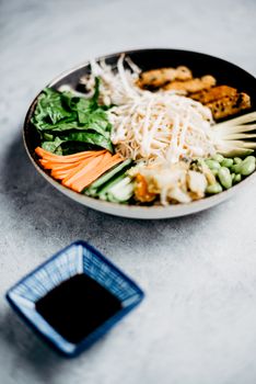 A vibrant Asian noodle bowl with fresh vegetables and soy sauce for healthy dining.
