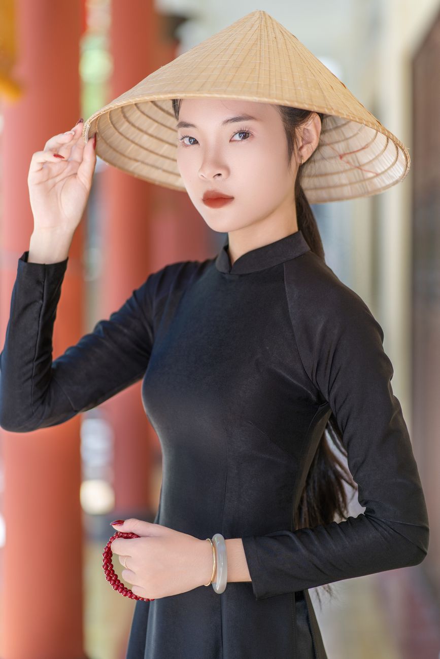 Portrait of a woman wearing a Vietnamese Ao Dai with a conical hat, showcasing traditional elegance.