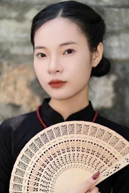 Portrait of a woman holding a decorative fan, showcasing elegance.