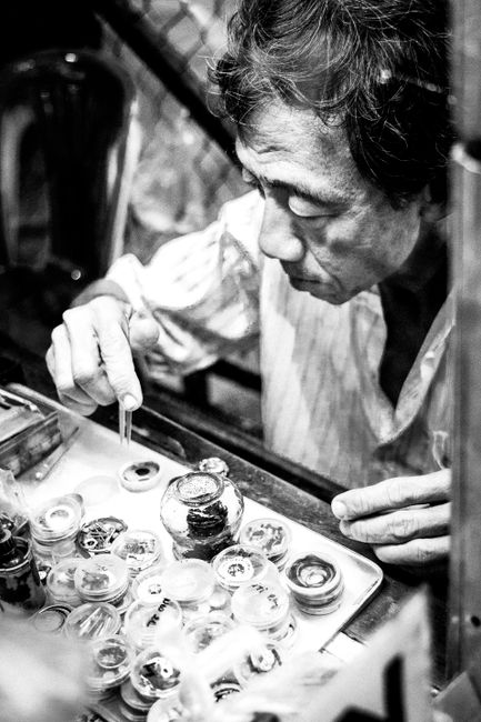 Black and white portrait of a focused artisan creating intricate crafts in Ho Chi Minh City, Vietnam.