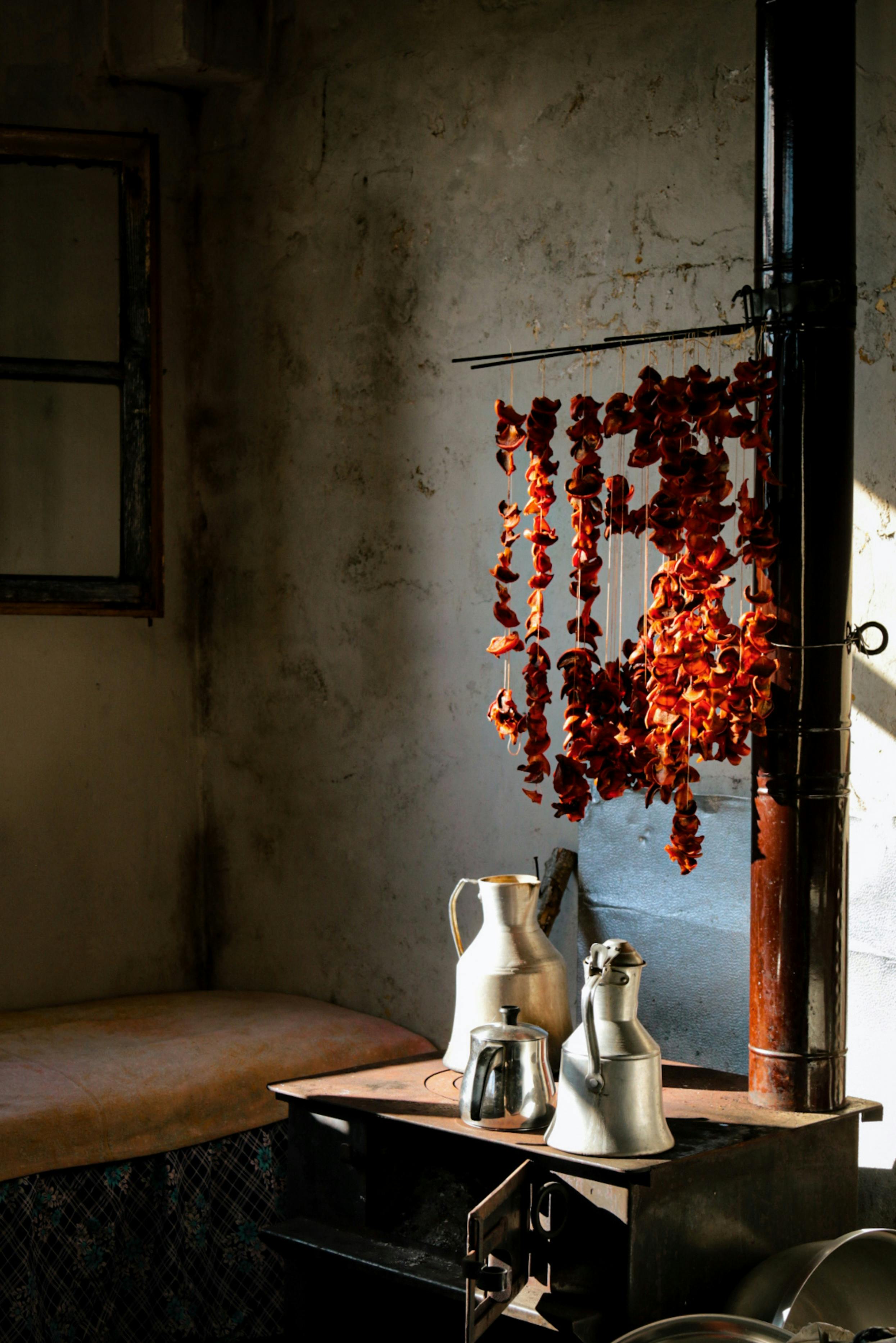 A cozy kitchen corner in Pazar, Rize, Türkiye with dried peppers and metal jugs on a stove.