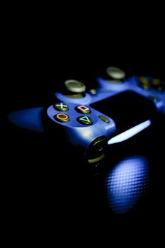 Close-up of a blue gaming controller illuminated on a dark carbon fiber surface.