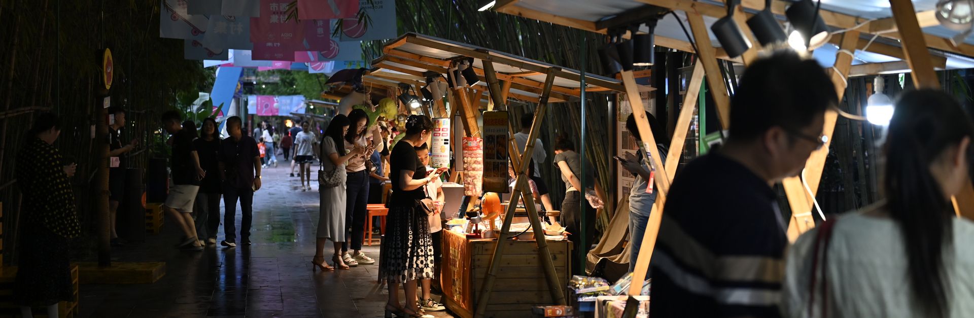 Bustling night market with vibrant stalls, lights, and visitors enjoying the lively ambiance.