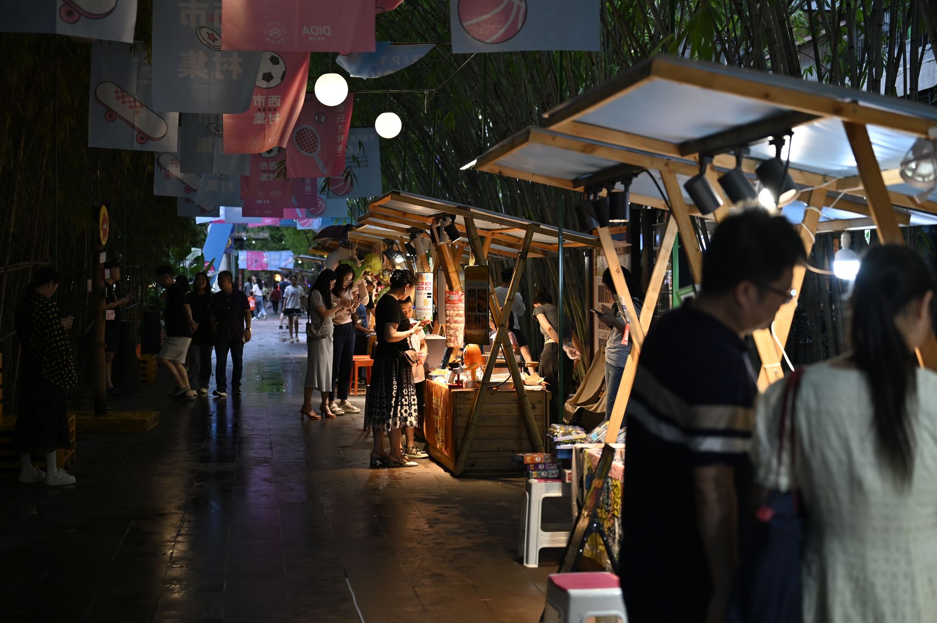 Bustling night market with vibrant stalls, lights, and visitors enjoying the lively ambiance.