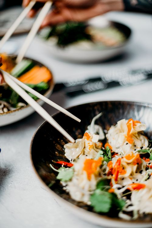 Free A close-up of delicious dumplings topped with fresh vegetables, captured with a shallow depth of field. Stock Photo