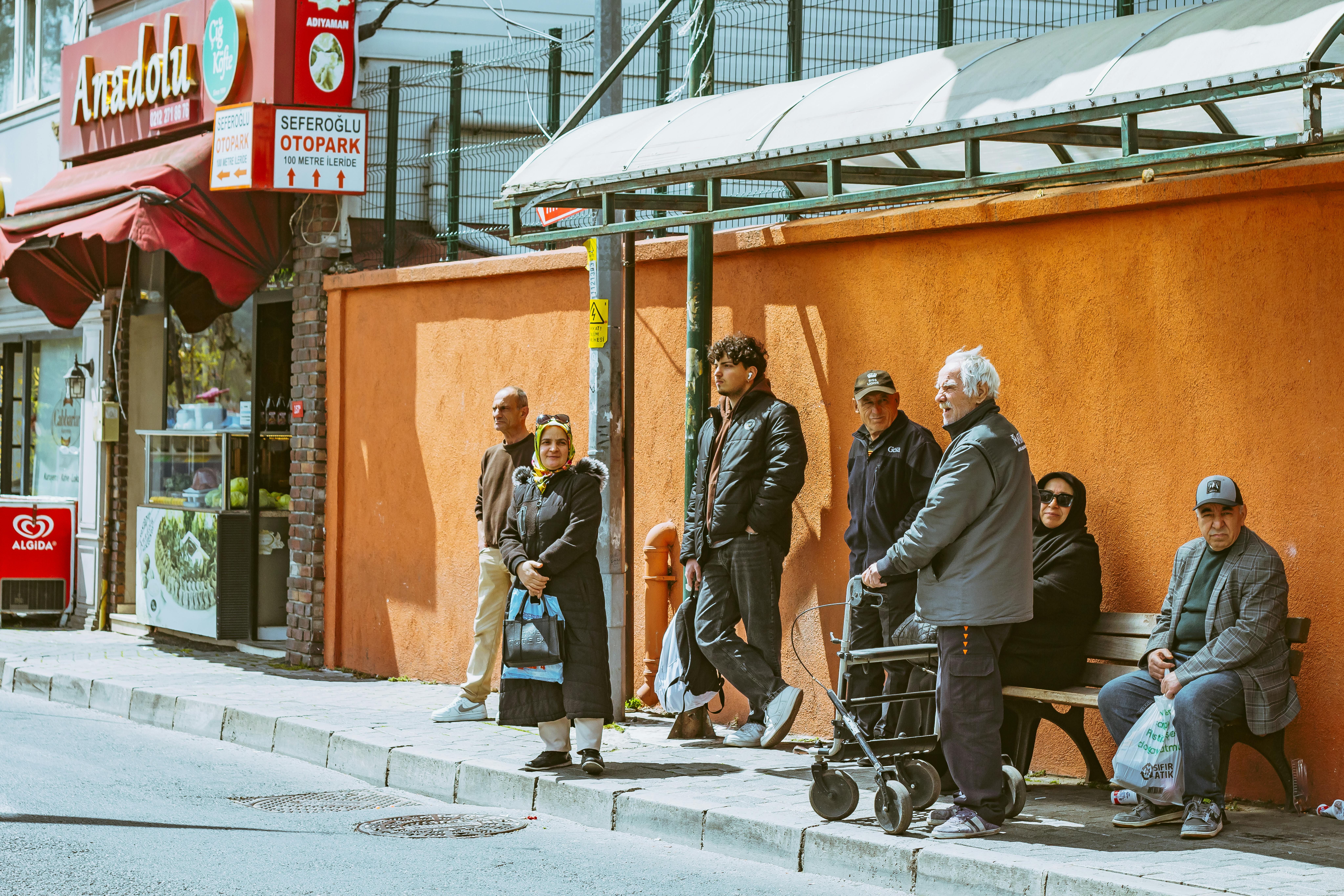 Belçika'nın tarihi mimarisi eşliğinde bir kafede oturan, Türk ve yerel kültürü bir araya getiren sosyal etkileşim ve günlük yaşam sahnesi.