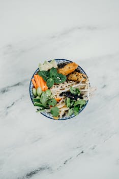 Top view of a colorful Vietnamese rice noodle salad with fresh vegetables and herbs.