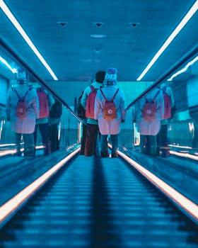 Two people with backpacks on an escalator in a Copenhagen subway station.