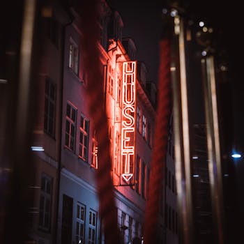 Captivating neon sign of Huset illuminates a Copenhagen street at night, showcasing urban nightlife.