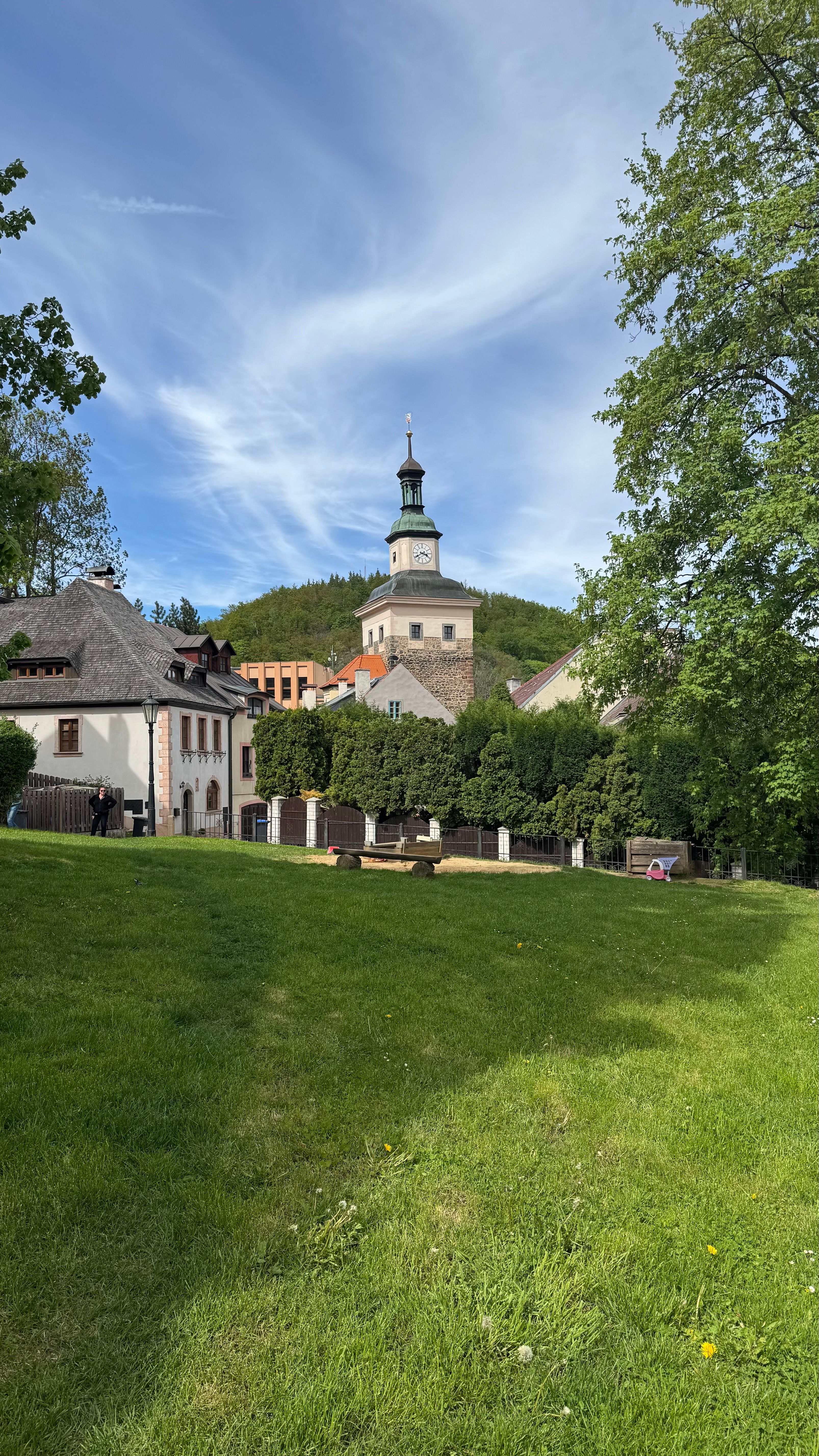 Idyllic European village scene with historical architecture and lush greenery under a clear sky.