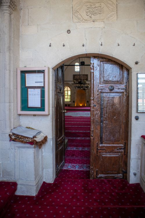 Free Open wooden door leading to the interior of a historic mosque in Elazığ, Türkiye. Stock Photo