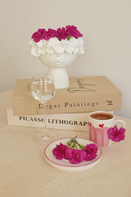 Artistic table with pink flowers, Degas and Picasso books, and coffee cup.